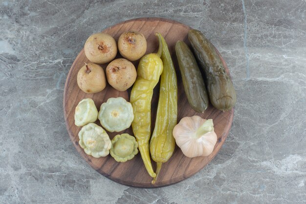 Top view of various kinds of pickle on wooden board.