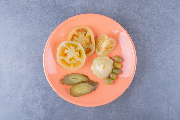 オレンジ色のプレート上のさまざまな種類の野菜のピクルスの上面図。