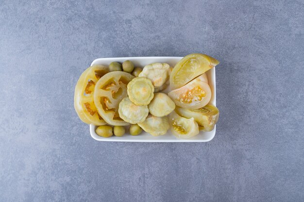 Top view of various kinds of vegetable pickle on white plate.