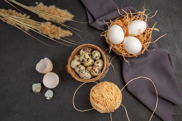 Top view of various organic eggs in a brown pot rope spike black towel on dark background