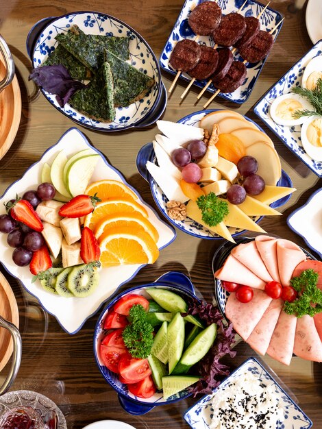 Top view of various plates of food for breakfst fruit salads fried eggr with herbs ham