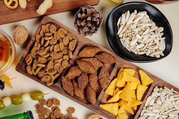 Free photo top view of various salty beer snacks bread crackers corn cones  sunflowers seeds nuts and pickled olives on white