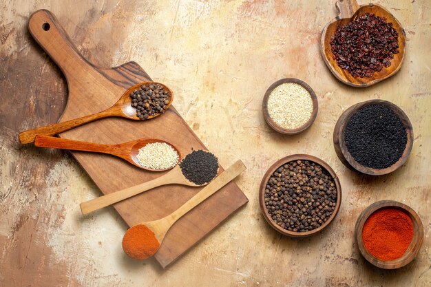 Top view of various spices in small brown pots and cutting board