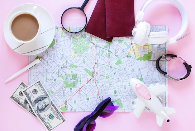 Top view of various traveler accessories and cup of tea on pink background