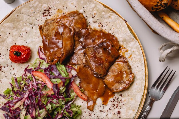 Top view veal meat in sauce on pita bread with vegetable salad