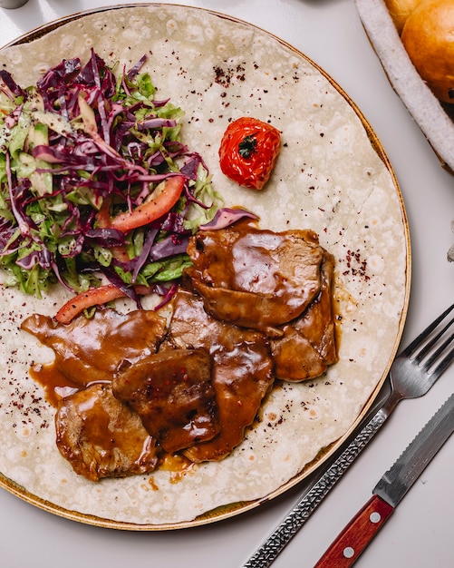 Top view veal meat in sauce on pita bread with vegetable salad