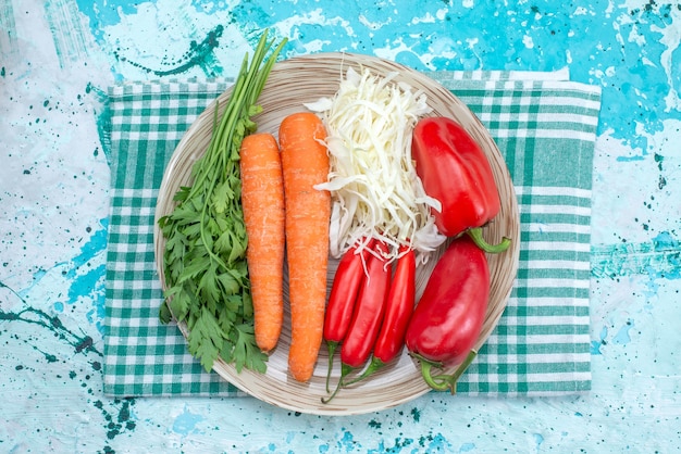 Free photo top view vegetable composition cabbage carrots greens and red spicy peppers on the bright-blue desk vegetable food meal healthy color