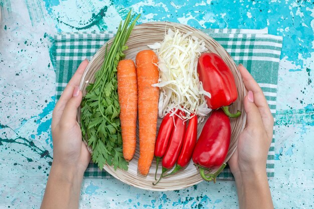 Top view vegetable composition cabbage carrots greens and red spicy peppers on the bright-blue table vegetable food meal healthy color