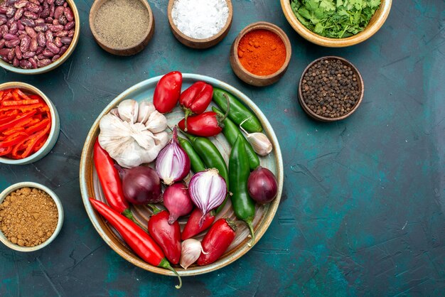 Top view vegetable composition onions garlics peppers seasonings on the dark-blue background food meal ingredient product color