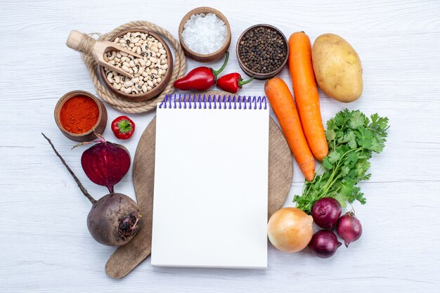 Top view vegetable composition with fresh vegetables raw beans carrots notepad and potatoes on the white desk food meal vegetable salad