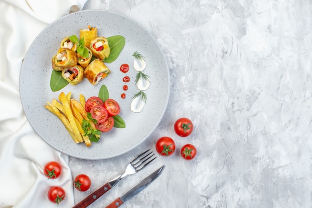 Foto gratuita vista dall'alto patè di verdure rotoli con pomodori e patatine fritte all'interno della piastra sulla superficie bianca