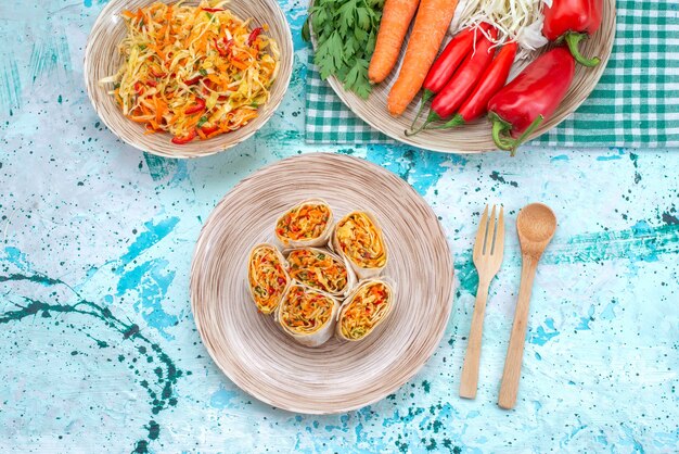 Top view vegetable rolls sliced along with fresh vegetable salad on the bright-blue desk vegetable food meal salad roll