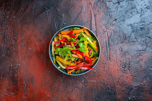 Top view vegetable salad in bowl on dark red table free space