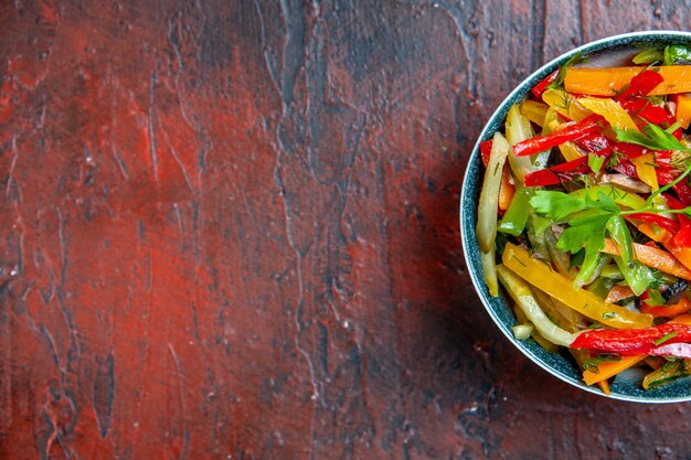 Top view vegetable salad in bowl on dark red table with free place