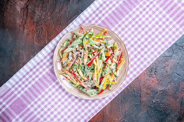 Бесплатное фото Вид сверху овощной салат на тарелке на скатерти на темно-красном столе свободное место