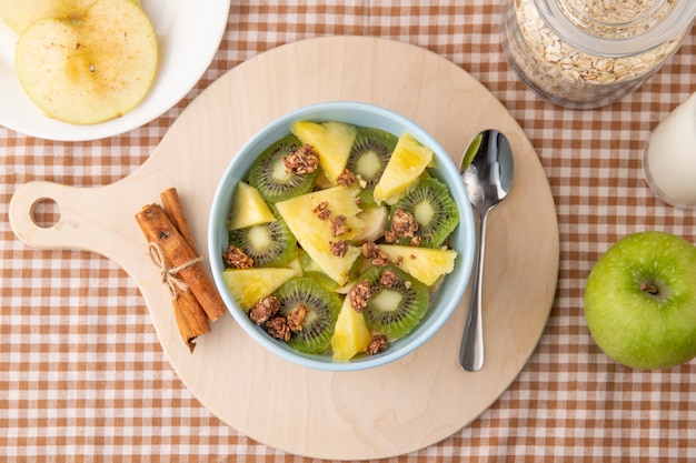 Foto gratuita insalata di verdure vista dall'alto con kiwi ananas e cannella su una tavola con un cucchiaio