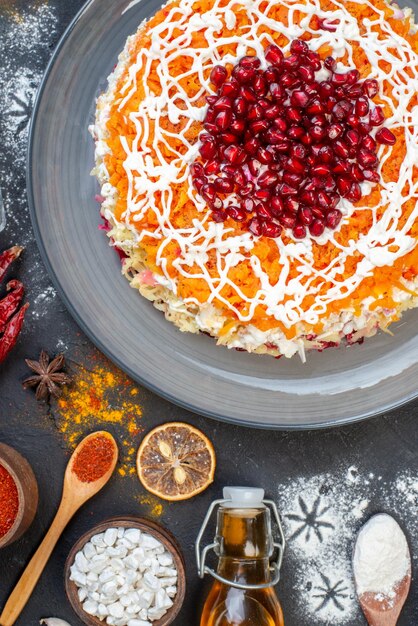 Top view vegetable salad with pomegranates and different ingredients on dark surface