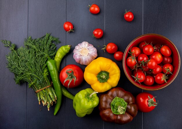 Top view of vegetables as bunch of dill pepper garlic tomato on black surface