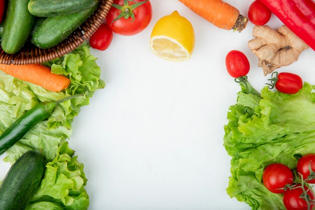 Top view of vegetables as carrot lettuce pepper tomato ginger with lemon on white background with copy space