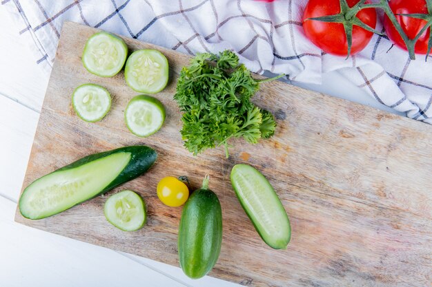 布と木の表面にトマトとまな板の上のキュウリトマトコリアンダーとして野菜のトップビュー