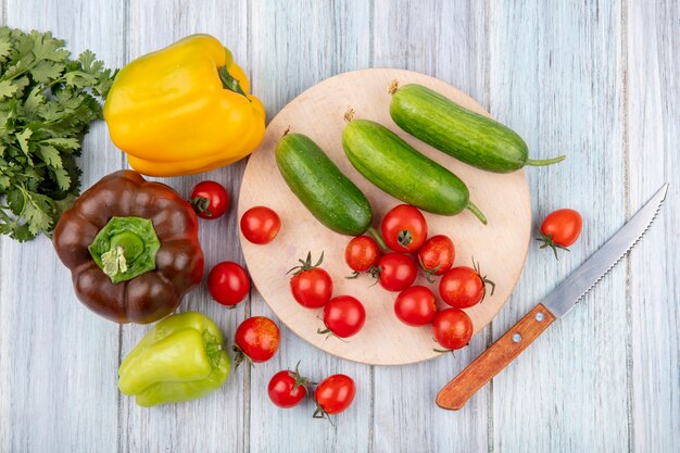 コショウのコリアンダーと木製の表面にナイフでまな板の上のキュウリトマトとして野菜のトップビュー