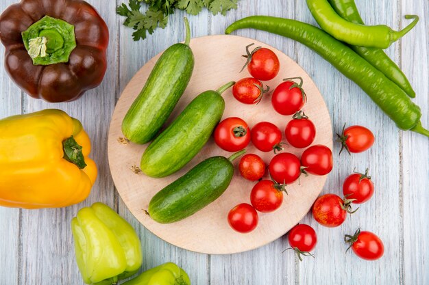 Top view of vegetables as cucumber tomato on cutting board with pepper on wooden surface