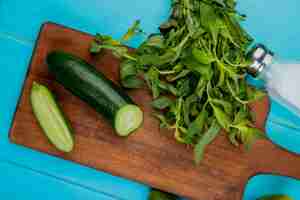 Foto gratuita vista superiore delle verdure come cetriolo e menta tagliati sul tagliere con sale sulla superficie del blu