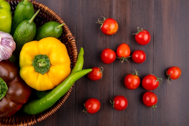 Free photo top view of vegetables as pepper cucumber in basket and tomatoes on wooden surface