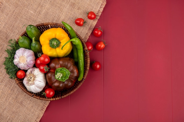 Взгляд сверху овощей как перец укропа томата огурца перца в корзине на вретище и красной поверхности