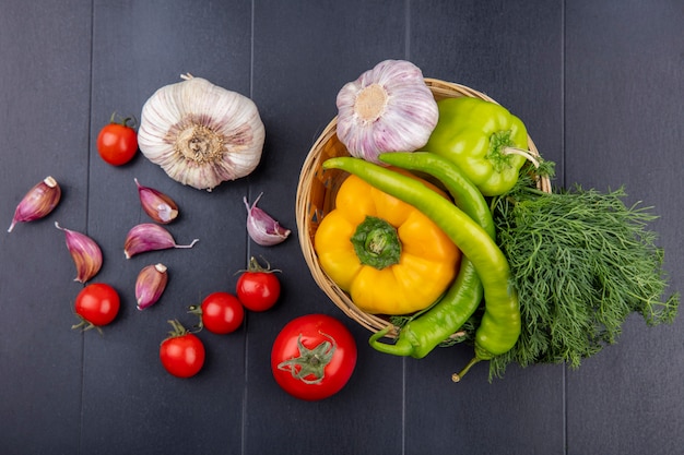 Vista superiore delle verdure come aglio nel pepe aglio aneto in cestino e pomodori spicchi d'aglio sulla superficie nera