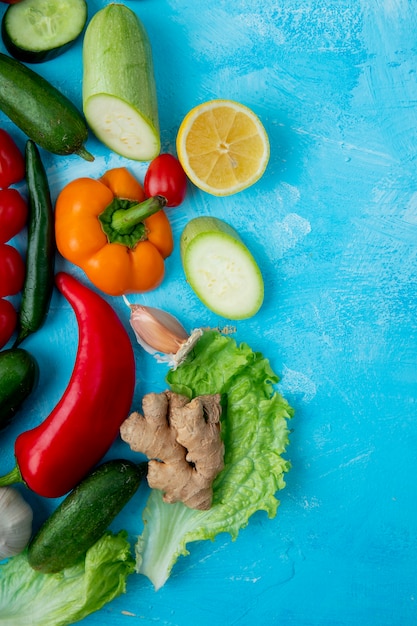 Free photo top view of vegetables as pepper lettuce ginger and others on left side on blue surface