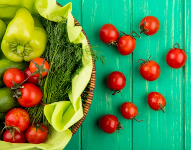 Vista superiore delle verdure come merce nel carrello dell'aneto del cetriolo del pomodoro del pepe su superficie verde