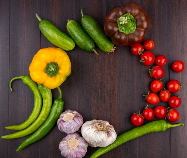 Top view of vegetables as pepper tomato cucumber garlic on wooden surface