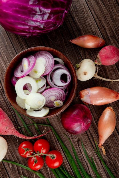 Top view of vegetables as sliced and whole onion tomato radish cabbage on wooden background