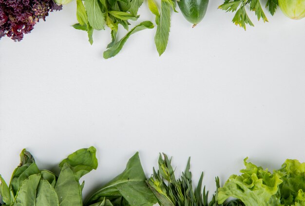 Top view of vegetables as spinach mint basil cucumber lettuce on white surface with copy space