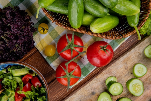 Вид сверху овощей как томатный огуречный базилик с овощным салатом на деревянной поверхности