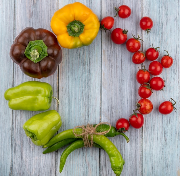 Free photo top view of vegetables as tomato and pepper set in round shape on wooden surface