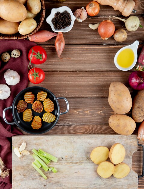 Top view of vegetables as tomato potato garlic with potato chips butter black pepper on wooden background with copy space