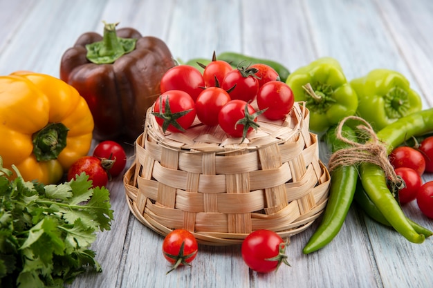 Top view of vegetables as tomatoes on basket with coriander peppers and tomatoes around on wooden surface