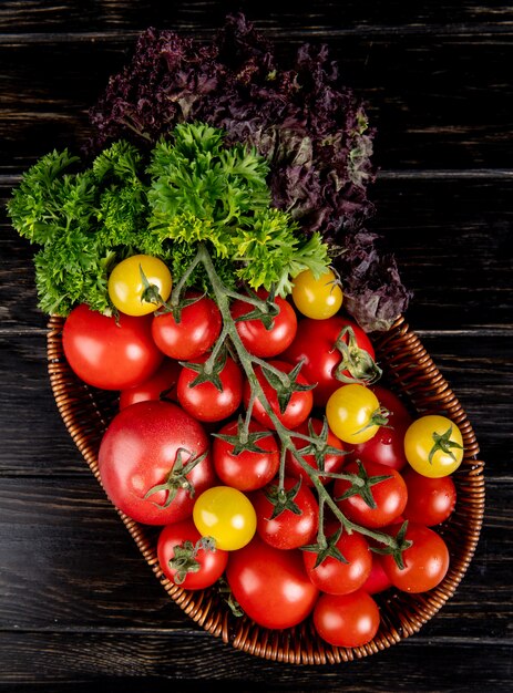 Top view of vegetables as tomatoes coriander basil in basket on wood