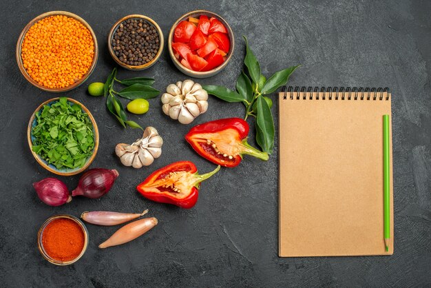 Top view of vegetables bowl of lentil herbs spices tomatoes bell pepper notebook pencil