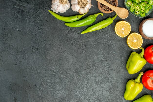 Top view vegetables composition tomatoes bell-peppers and garlics on dark background