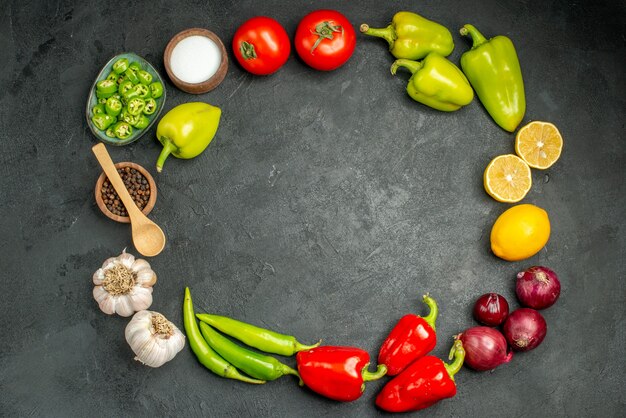 Top view vegetables composition tomatoes bell-peppers and garlics on dark background