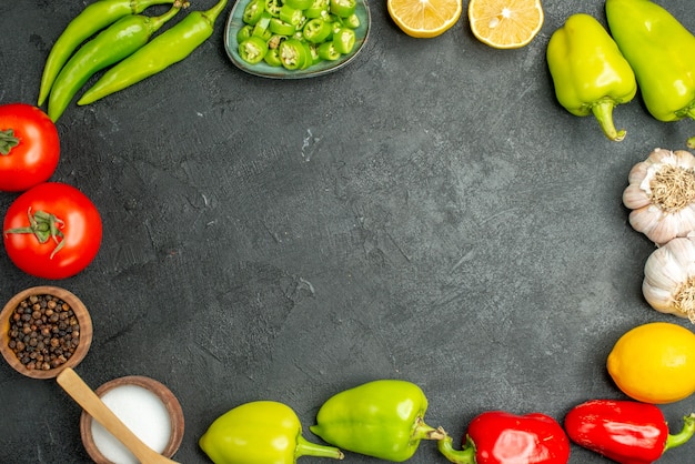 Top view vegetables composition tomatoes bell-peppers lemon and garlics on a dark background