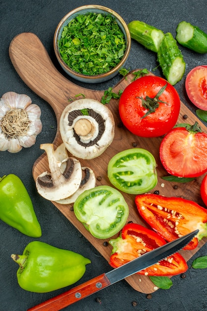 Top view vegetables cucumbers green and red tomatoes bell peppers knife on cutting board