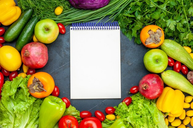 Top view vegetables and fruits lettuce tomatoes cucumber dill cherry tomatoes zucchini pomegranate persimmon apple notebook on center