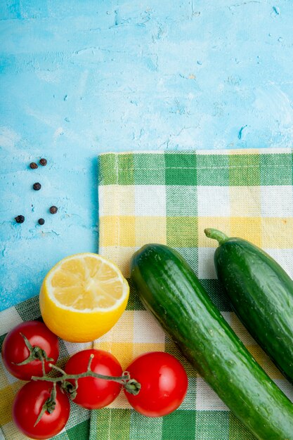 Top view of vegetables, lemon and pepper spice on cloth on blue surface
