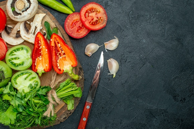 Top view vegetables mushrooms tomatoes bell peppers greens on rustic board