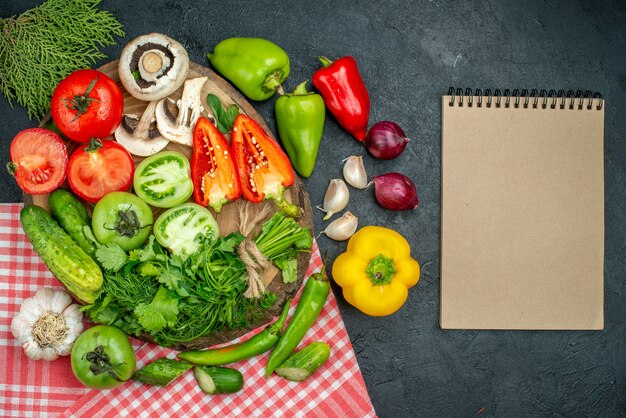 Top view vegetables mushrooms tomatoes red and green bell peppers greens on wood board