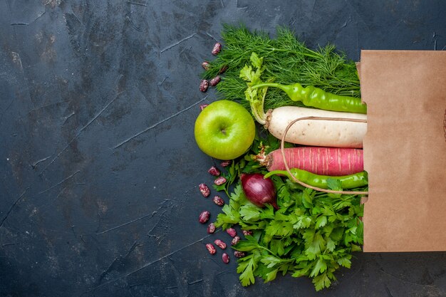 Top view vegetables radish greens hot pepper red onion apple on dark background